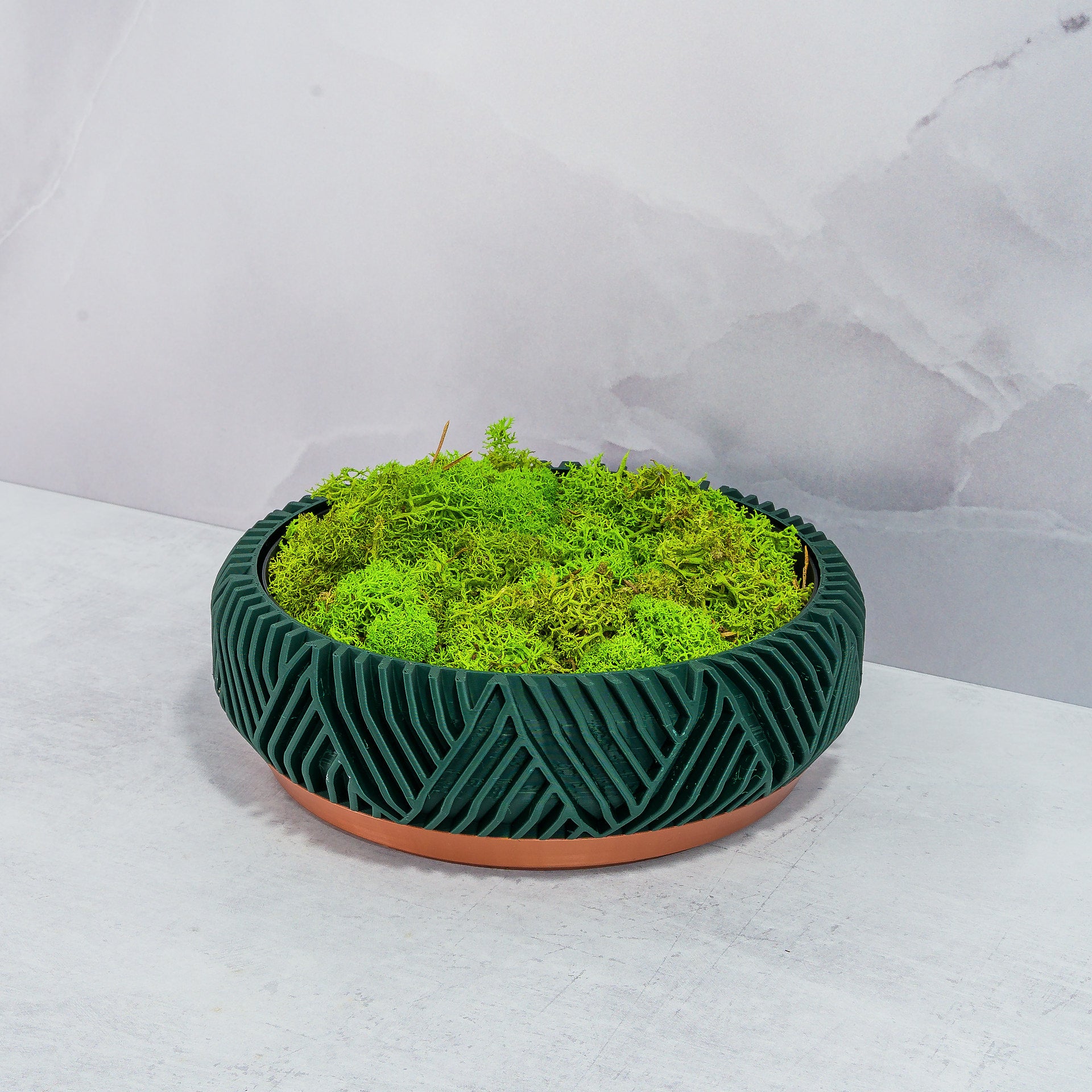 "PEAK bowl planter displayed at an angle with preserved moss in a custom insert, highlighting copper base and forest pattern."
