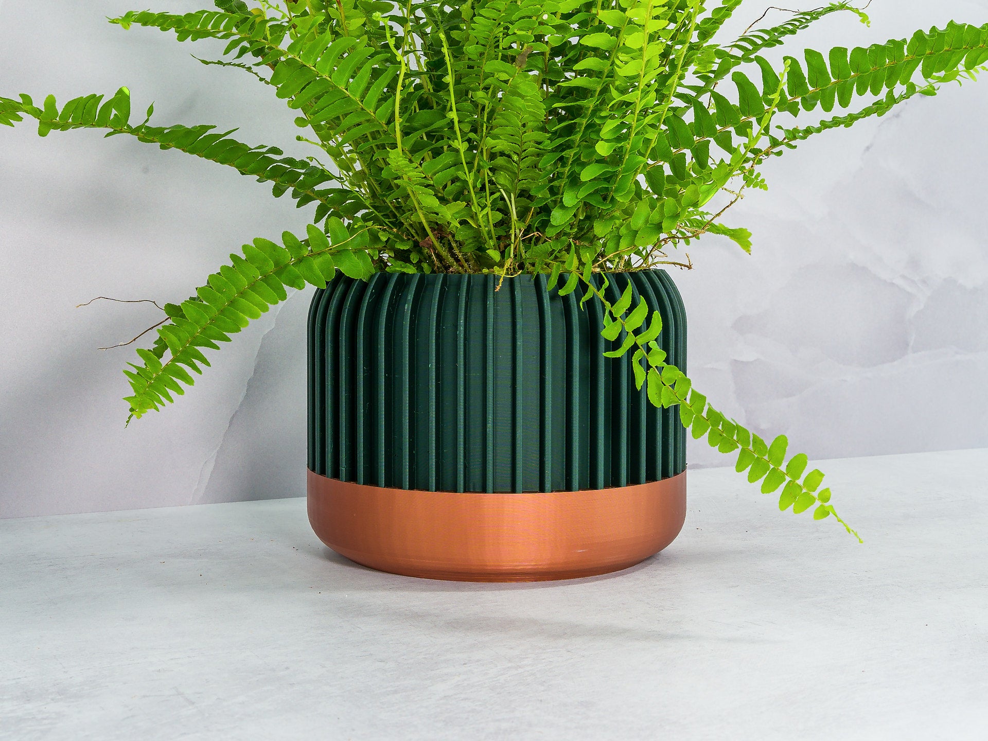 Angled with Fern: "Angled view of LINEAR planter with copper base and forest pattern, showcasing a fern plant."
