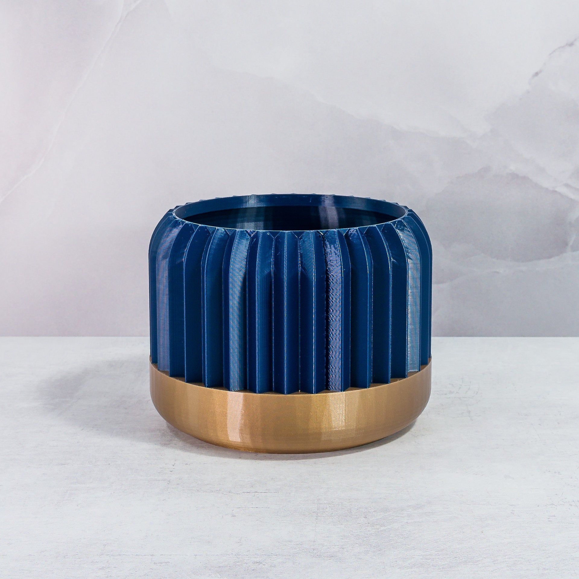 Front Facing: "TRILINEAR planter with gold base and navy pattern, front view."
