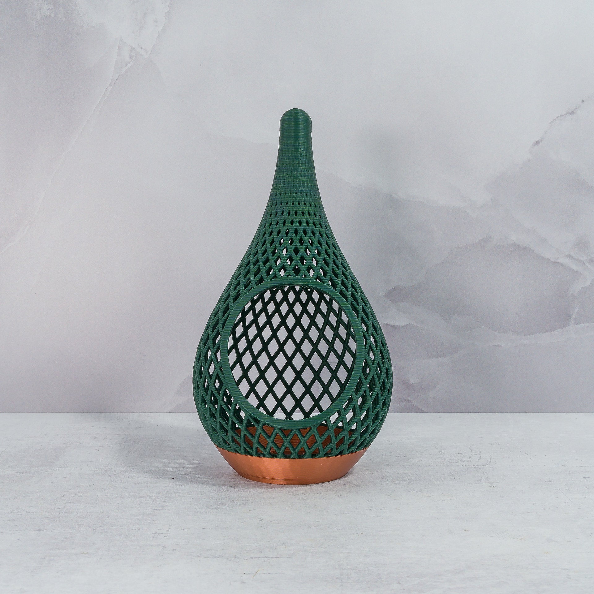 "Sitting, front-facing, empty COPPER AND FOREST GREEN TEARDROP planter, showcasing its elegant design and deep green forest pattern."
